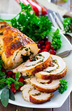 sliced turkey breast on a white plate with cranberries and parsley