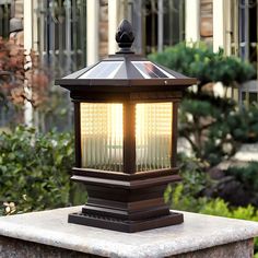 a light that is sitting on top of a cement block in front of some bushes