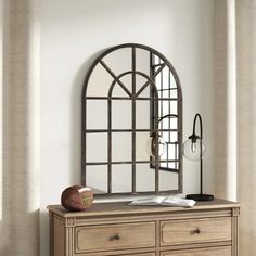 an arched mirror on top of a dresser