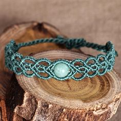 a green beaded bracelet sitting on top of a piece of wood