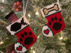 two christmas stockings hanging from a tree with dog paw prints and hearts on the socks