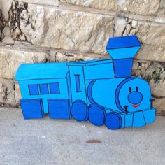 a blue wooden train sitting next to a brick wall