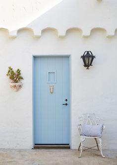 a blue door and chair in front of a white building