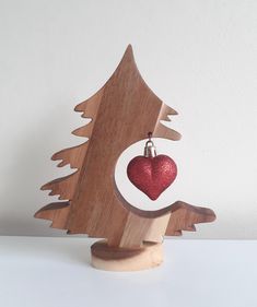 a small wooden christmas tree with a red heart hanging from it's center piece