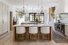 a large kitchen with an island in the middle and three stools at the end