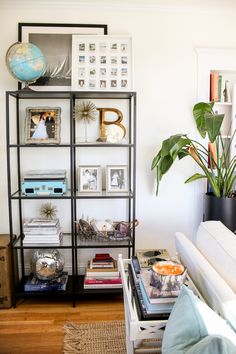 a living room filled with furniture and a book shelf next to a plant on top of a table