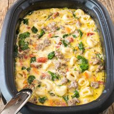 a casserole dish with meat, cheese and spinach in it on a wooden table