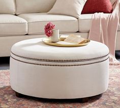 a coffee table with a book and cup on it in front of a white couch