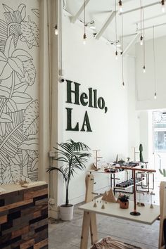 the inside of a building with tables and chairs in front of a wall that says hello la