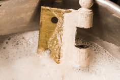 a metal bowl with some water and a wooden object in it's bottom half