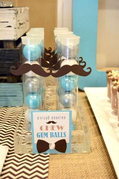 a table topped with bottles filled with blue and white candies next to cupcakes