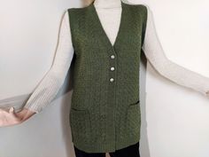 "This is a sleeveless sweater vest for women. This v-neck cardigan is very cozy and keeps your body warm in winter and also it's a seasonal outfit for all seasons. It's made of soft and high quality green fibers that is not itchy on your skin so it's very comfortable. This v-neck vest is a multipurpose waistcoat; it can be used as a casual knit jacket or a chic sweater vest for a young adult woman or mothers and grandmothers. It has three buttons and two packets. This tunic vest is a half handwoven tricot product. Other color options of this vest is also available in the shop. The height of the woman model in the photos 168cm (5'6\"), her bust 87cm (35\"). She is wearing medium one. Please see below for detailed size information: DIMENSIONS: Medium: Length: 72cm (28,4\") / Bust around: 104 Green Sweater Vest For Winter Layering, V-neck Vest With Buttons For Winter, V-neck Button Vest For Winter, Winter Workwear Green Vest, Green Winter Vest For Layering, Green Winter Layering Vest, Green Winter Workwear Vest, V-neck Vest With Pockets For Fall, Green Winter Vest With Buttons