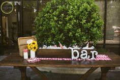 a picnic table with sunflowers and wine bottles on it in front of a building