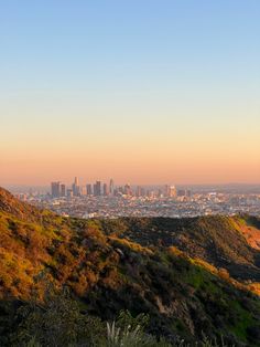 the city is seen in the distance as it sits on top of a hill with lots of trees