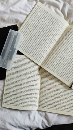 three open books on top of each other next to a plastic container with an eraser