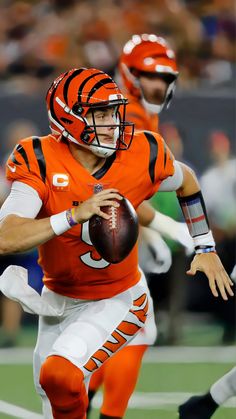 a football player in an orange uniform is running with the ball and has his arm extended