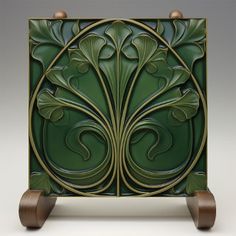 an art deco style cabinet with wood legs and green paint on the front, featuring leaves and swirls