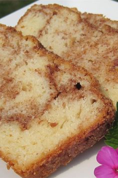 two pieces of bread sitting on top of a white plate next to a pink flower