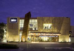 an illuminated building with people standing outside at night