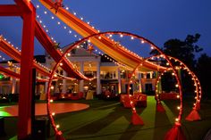 an outdoor event with red and orange decor, lights and decorations on the grass at night