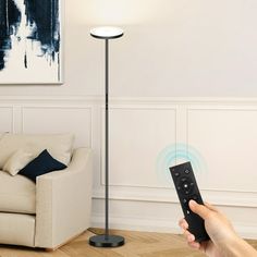 a person holding a remote control in front of a couch with a painting on the wall