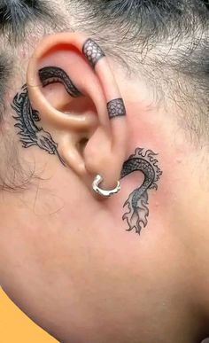 a man with a dragon tattoo on his ear and behind the ear is a snake