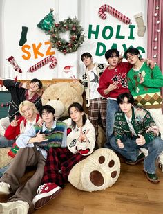 the group is posing for a photo with their teddy bear and christmas decorations on the wall behind them