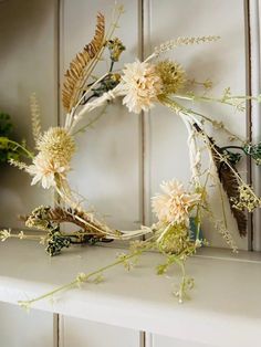 a wreath with dried flowers and feathers on a mantle