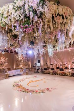 an elaborately decorated dance floor with chandeliers and flowers hanging from the ceiling