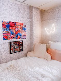 a white bed sitting in a bedroom next to a wall with pictures hanging on it