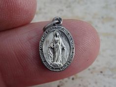 "Religious antique silver ( MARKED ) charm medallion pendant miraculous medal of Immaculate Conception of Holy Virgin Mary of Graces.  November 27 marked the 177th anniversary of the Medal of the Immaculate Conception, popularly known by Catholics the world over as the Miraculous Medal. The Miraculous Medal has a special place in the hearts of the Marians of the Immaculate Conception, since it paved the way for the Church's official declaration of the dogma in 1854. The medal is striking because Our Lady herself presented the familiar design. The front of the medal depicts Mary standing on a globe, with the head of a serpent beneath her feet. Circling the oval-shaped medal is the signature, \"O Mary, conceived without sin, pray for us who have recourse to thee.\" On the reverse, twelve sta Silver Miraculous Medal Pendant, Silver Pendant With Miraculous Medal, Immaculate Conception, St Therese, Pray For Us, Miraculous Medal, Our Lady, Virgin Mary, Collectable Items