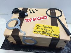 a cake that is shaped like a suitcase and has a sign on it saying top secret