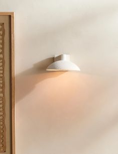 a white wall light mounted on the side of a wall next to a framed photograph