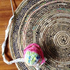 a piece of woven material sitting on top of a wooden floor next to a ball of yarn