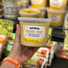 a hand holding up a jar of vegan mac in front of some other items