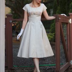 a woman in a white dress standing on a wooden fence