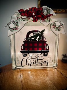 a glass block with the words merry christmas on it and a red plaid truck in the background