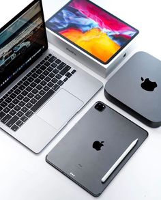 an apple laptop computer sitting on top of a white table next to two macbook pros