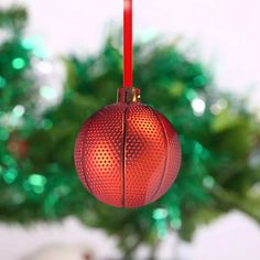 a red glass ornament hanging from a red string next to a green christmas tree