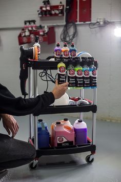 a man sitting on the floor next to a cart filled with different types of cleaning products