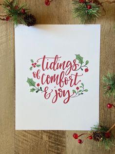 a christmas card with red lettering and holly leaves on it, surrounded by pine cones