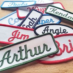 six embroidered name tags on a wooden surface