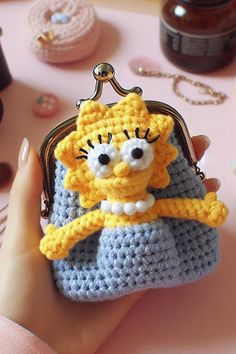 a hand holding a small crocheted purse with a cartoon character on the front