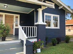 a blue house with white trim and flowers on the front porch