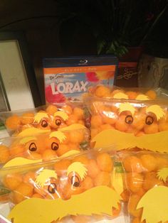 oranges in plastic bags with faces drawn on them sitting next to a box of lorax