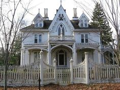 a large white house sitting next to a lush green forest