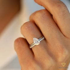 a close up of a person's hand holding a ring with a diamond on it