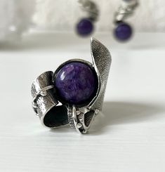 Handmade ring with natural charoite stone set in high-quality sterling silver. Thie ring has a magical purple color stone in a round shape, a textured surface with granulation, and a spiral part on it. Charoite is named after the Chara River that runs through the Sakha Republic of Siberia. It is a rare stone that is only found in Siberia. Do you know? This stone is all about positive transformation. Charoite cleanses the aura and chakras by transmuting negative energy into healing. It opens our hearts and stimulates unconditional love. Re-energizes, reducing stress and worry.  A balancer of body, mind, and spirit, here's how Charoite can bring the violet ray of light into your life. FULL DETAILS ► Gemstone: Natural charoite  ► RING  size: all sizes are available (choose from the option) We Elegant Purple Rings With Natural Stones, Elegant Sterling Silver Amethyst Ring With Natural Stones, Unique Nickel Free Purple Ring, Elegant Purple Nickel-free Rings, Unique Purple Nickel-free Ring, Unique Nickel-free Purple Ring, Handmade Spiritual Purple Crystal Ring, Handmade Purple Crystal Spiritual Ring, Adjustable Purple Cabochon Ring