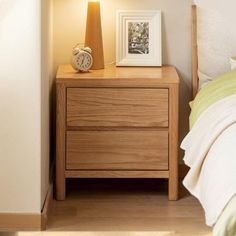 a nightstand with a clock on it next to a night stand and a framed photograph