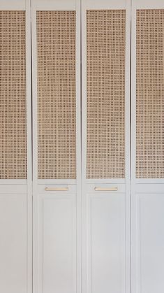 an empty room with white walls and wicker panels on the doors, in front of a bench